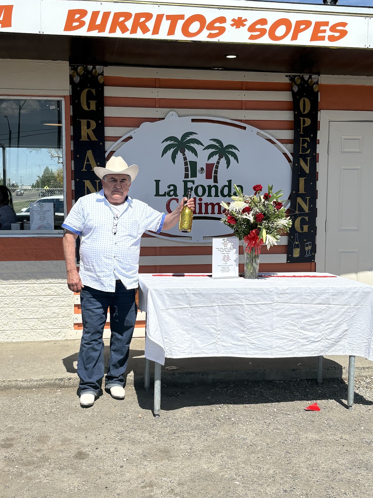 The owner of La Fonda Colima beside the restaurant sign on opening day